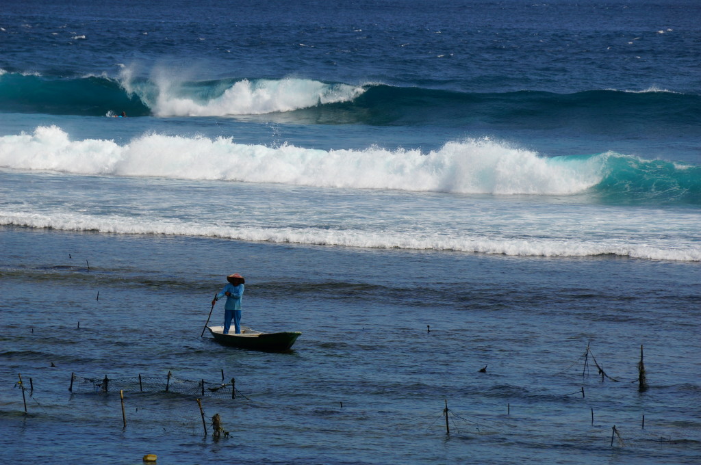 Een local trotseert de hoge golven aan de kust van Nusa Lembongan